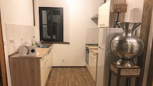 A compact kitchen with white cabinets, a wooden countertop, a toaster, and a decorative metal vase. - Holiday apartment PENZLIN in a maritime style near Radeberg (Leppersdorf)