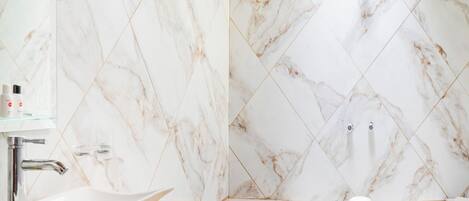 A bathroom with a marble vanity, a freestanding bathtub, and a shower area.
