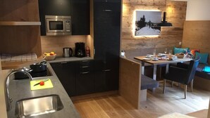 A modern kitchen with a built-in microwave, a coffee maker, and a sink. There is a dining area with a table and chairs, and a cozy seating area with a fur rug. - Appartements Schweiberer, exclusive apartment Hochfügen (Ried im Zillertal)