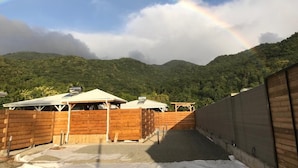 Un espacio al aire libre cubierto con valla de madera, una estructura techada y vistas a una cadena montañosa boscosa.