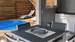 Un patio con mesa y sillas, una piscina y una valla de madera.