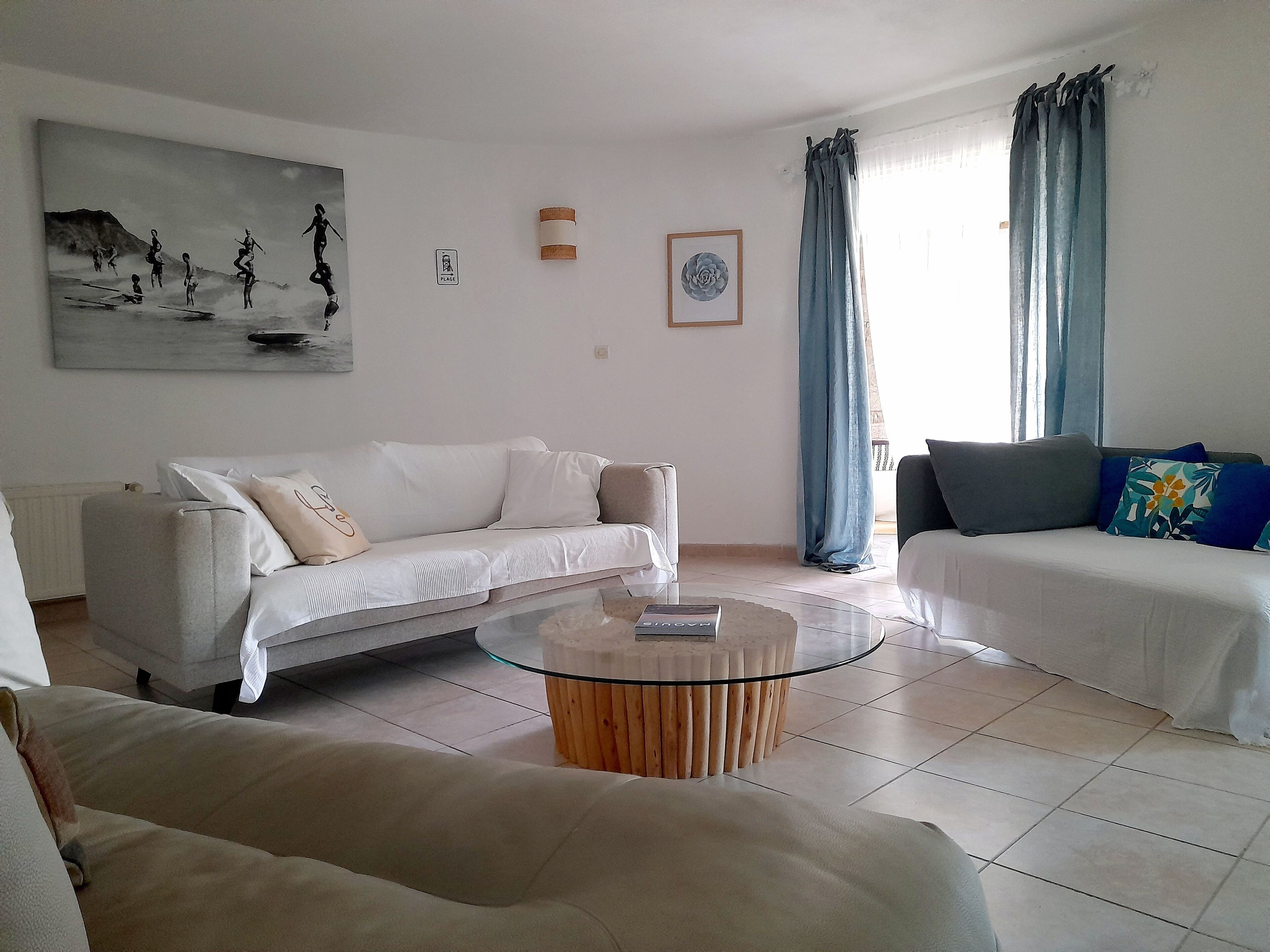 A living room with a white sofa, a glass coffee table, and a painting on the wall.