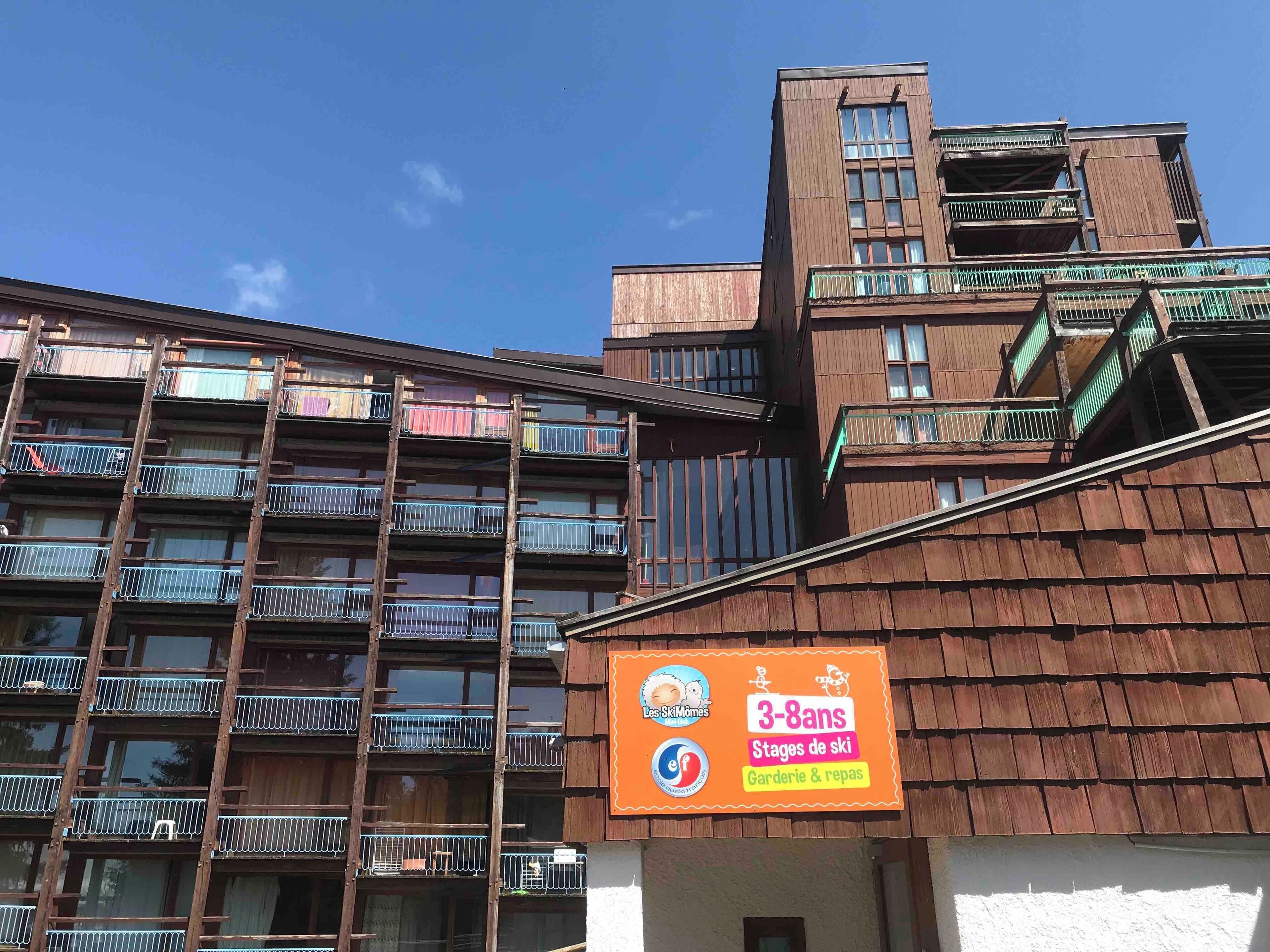 A multi-story building with balconies and a sign advertising a ski stage for ages 3-8.
