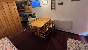Una cocina acogedora con una mesa y sillas de madera, un televisor y un refrigerador.