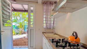 Une cuisine équipée d’une cuisinière à gaz, d’un évier et d’une fenêtre donnant sur un espace verdoyant.