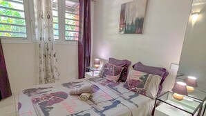 Une chambre à coucher avec un lit, une table de chevet, une lampe et une fenêtre avec des rideaux.