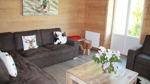 A cozy living room with a brown sofa, a wooden coffee table with flowers, and a painting on the wall. - 8/10 people cottage 110 m2  (les deux alpes)