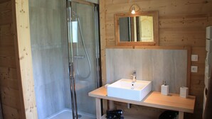 A wooden cabin bathroom with a glass shower enclosure, a white sink, and a mirror above it. - 8/10 people cottage 110 m2  (les deux alpes)