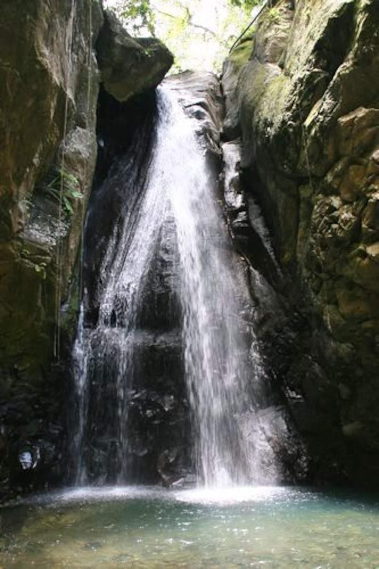 Une cascade se déversant le long d’une falaise rocheuse dans un bassin d’eau claire.
