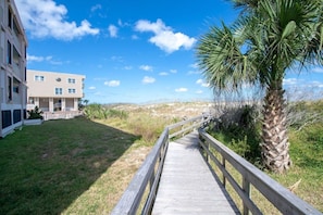 A wooden boardwalk leading to a building with a flat roof and multiple windows.