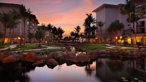 A resort with a serene water feature, palm trees, and a bridge connecting buildings.