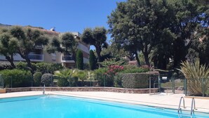 A clear blue swimming pool surrounded by a stone wall, with a metal fence and a gate. - Renovated apartment in Valescure, with pool and golf view, near the sea  (Saint-Raphaël)