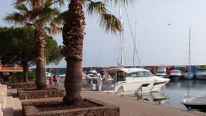 A marina with boats docked, palm trees, and a colorful mural in the background. - Renovated apartment in Valescure, with pool and golf view, near the sea  (Saint-Raphaël)