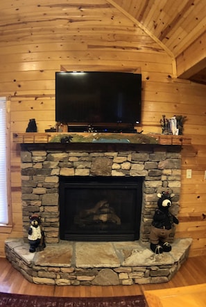 Cozy space with a stone fireplace, TV, and bear figurines.