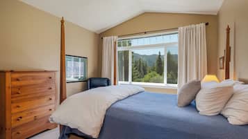 A bedroom with a bed, wooden dresser, and a window with curtains.