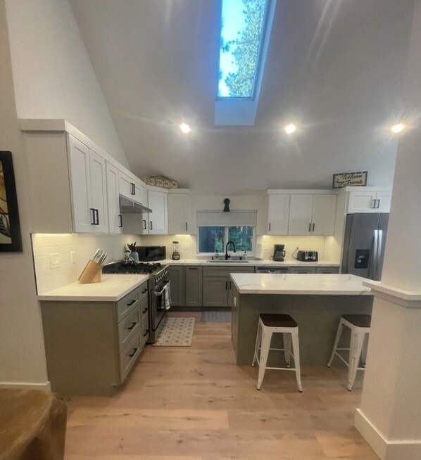 A modern kitchen with white cabinets, a central island, and a skylight.