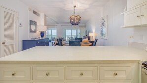 A spacious kitchen with a large island, white cabinetry, and a chandelier. - Direct Gulf Front Views ! Amazing Views ! (Sanibel)