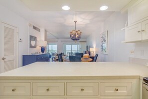 A spacious kitchen with a large island, white cabinetry, and a chandelier.