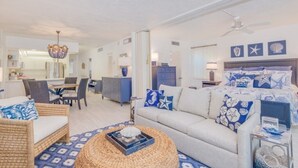 A well-lit, spacious room with a sofa, dining table, and a ceiling fan. - Direct Gulf Front Views ! Amazing Views ! (Sanibel)