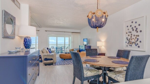 A modern dining area with a round table, wicker chairs, and a blue chandelier. - Direct Gulf Front Views ! Amazing Views ! (Sanibel)