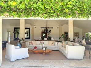 A spacious living area with a white sofa set, a wooden coffee table, and a hanging green plant.