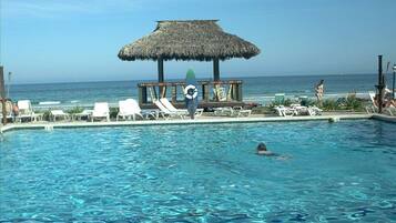 A pool area with lounge chairs and a thatched-roof structure.