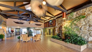 A spacious lobby with a high ceiling, stone wall, and indoor plants. - Oceanfront - Poolside - Steps to Beach & Tiki Bar (Daytona Beach Shores)