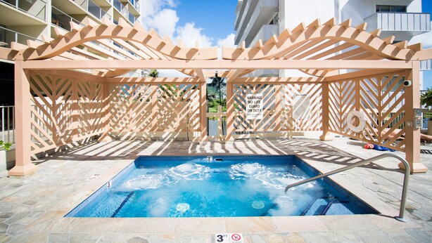 A pool area with a hot tub, surrounded by a wooden pergola, and a sign indicating a no life guard on duty. - Enjoy the Gorgeous Mountain, Canal and Golf Course Views #2120 (Honolulu)