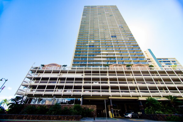 A multi-story hotel with a modern design, featuring a prominent entrance with a covered area and a parking lot visible in front.