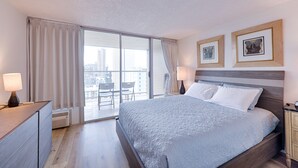 A hotel room with a large bed, a desk, a chair, and a view of the city through the window. - Enjoy the Gorgeous Mountain, Canal and Golf Course Views #2120 (Honolulu)