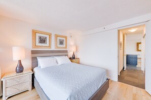 A neatly arranged bedroom with a bed, bedside tables, and framed pictures on the wall.