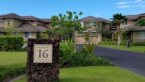 A residential area with numbered houses, well-maintained lawns, and a clear sky.