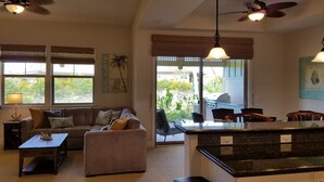 A spacious living room with a sofa, coffee table, and a kitchen area with a grill.