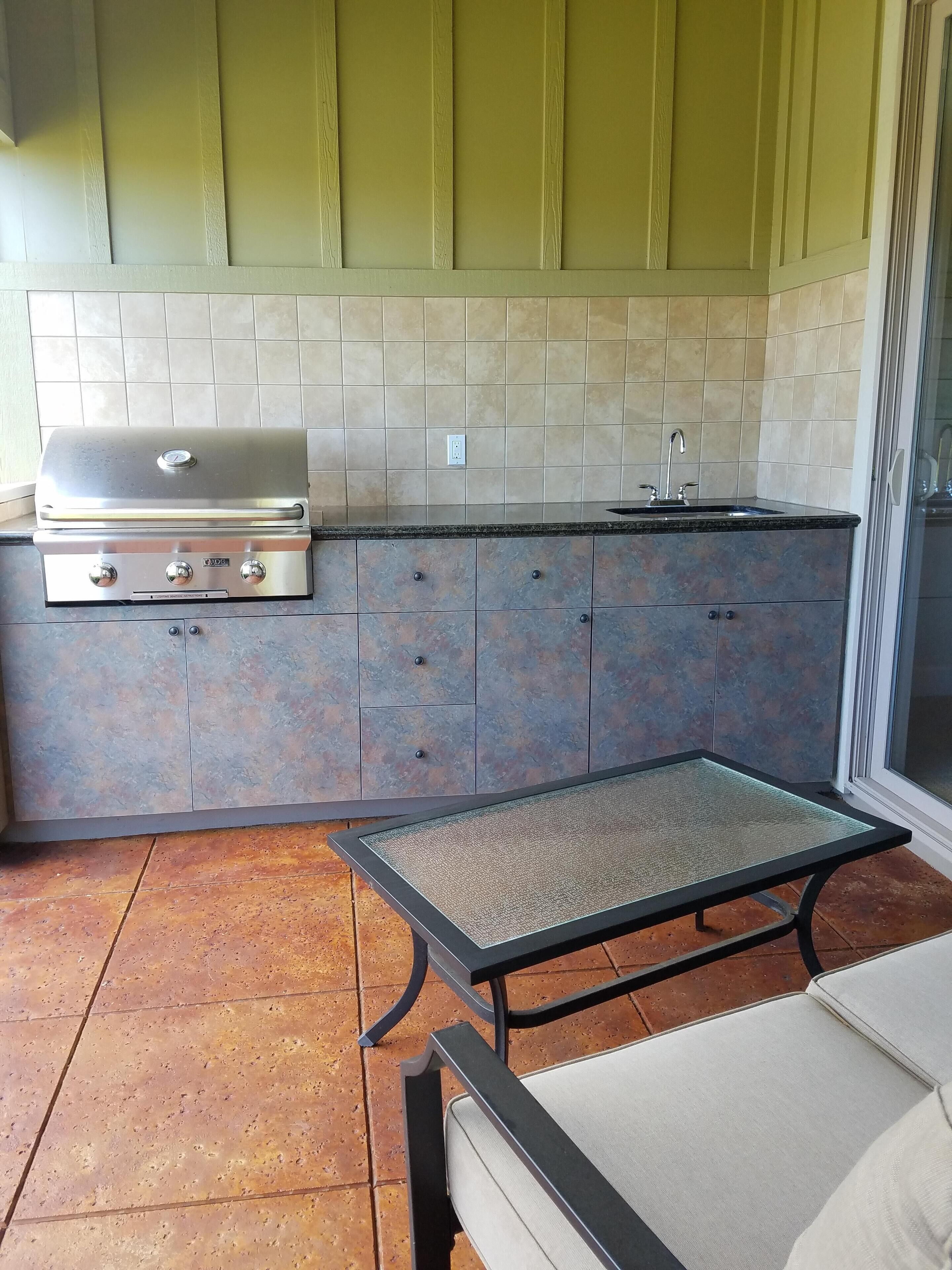 A kitchen with a built-in grill, a sink, and cabinets.