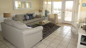 A living room with a beige sofa, a glass coffee table, and a patterned rug.