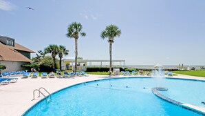 A swimming pool with lounge chairs and palm trees.
