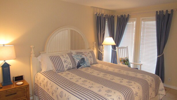 A bedroom with a bed, nightstand, lamp, and a window with curtains.