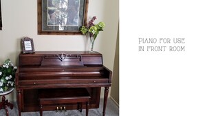 Un piano de cola en una habitación con un espejo y un jarrón de flores.