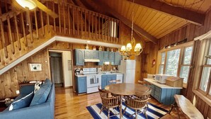 A cozy cabin-style kitchen with wooden floors, a dining table, and blue cabinets. - Unique Round House on Beech Mtn -Ski, Hike, Golf, Fish-Near Wineries & Parkway (Beech Mountain)
