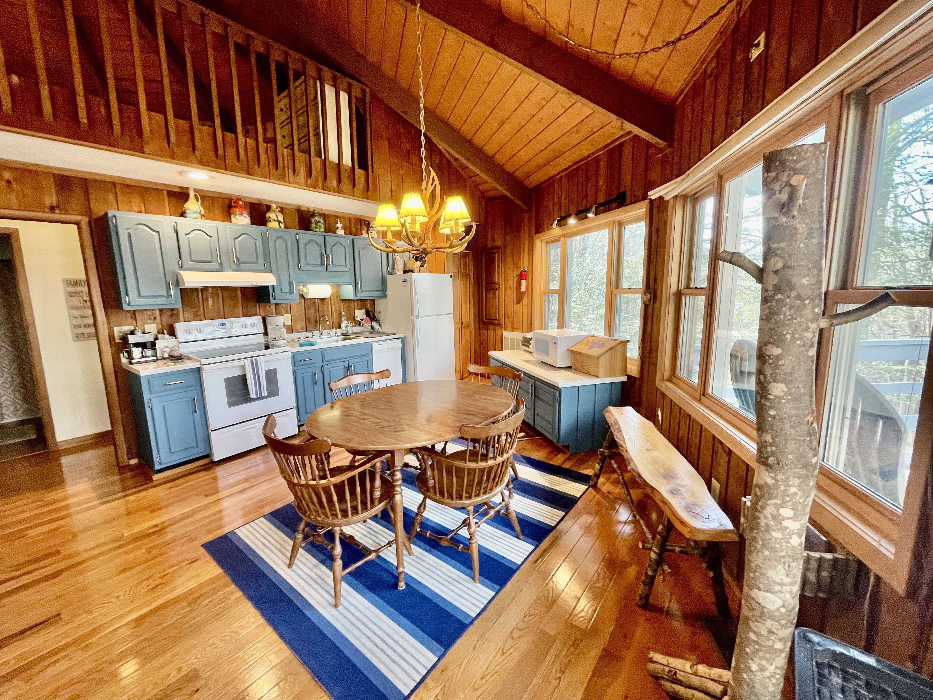 L’intérieur d’un chalet en bois comprend une cuisine, un coin repas et un banc placé près de la fenêtre.
