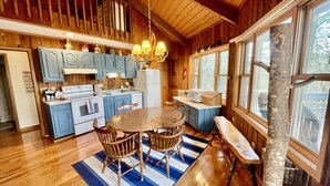 A wooden cabin interior with a kitchen, dining area, and a bench by the window. - Unique Round House on Beech Mtn -Ski, Hike, Golf, Fish-Near Wineries & Parkway (Beech Mountain)