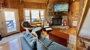 A cozy cabin interior with a stone fireplace, wooden walls, and a television mounted above it. - Unique Round House on Beech Mtn -Ski, Hike, Golf, Fish-Near Wineries & Parkway (Beech Mountain)