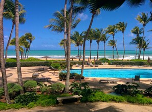 A poolside area with lounge chairs and a view of the ocean.
