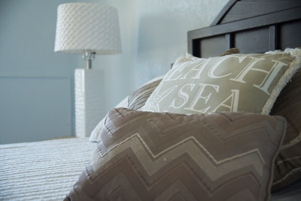 A bed with pillows, a lamp, and a wall.