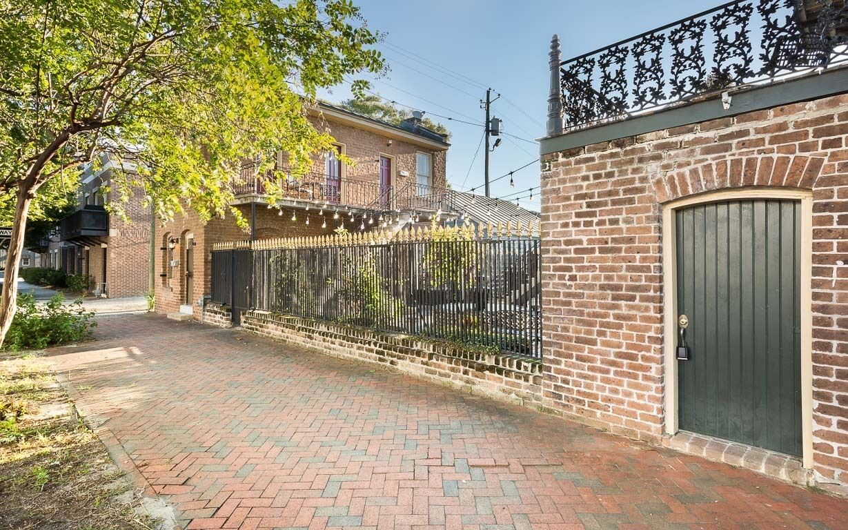 A brick building with a green door and a wrought iron fence.