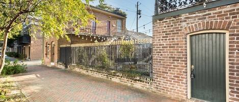A brick building with a green door and a wrought iron fence.