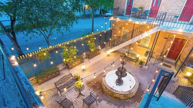 A rooftop patio with outdoor seating, a fountain, and string lights. - Grand Manor on Broughton Street w/ Parking, Courtyard by Lucky Savannah (Savannah)