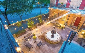 A rooftop patio with outdoor seating, a fountain, and string lights. - Grand Manor on Broughton Street w/ Parking, Courtyard by Lucky Savannah (Savannah)