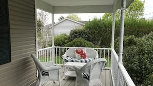 A covered porch with wicker furniture and a white railing. - Beautiful North Fork 3-Bedroom Home Steps Away from a Private Sandy Bay (Southold)