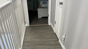 A wooden hallway with white railings and a door on the right. - Spacious 3bd 3ba, 1 min walk to private beach with 2 master king bed (Miramar Beach)
